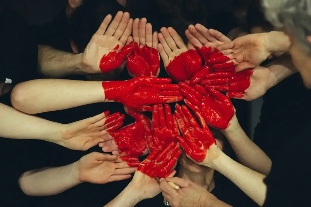Photo of many hands painted red and joined to make a red heart shape
