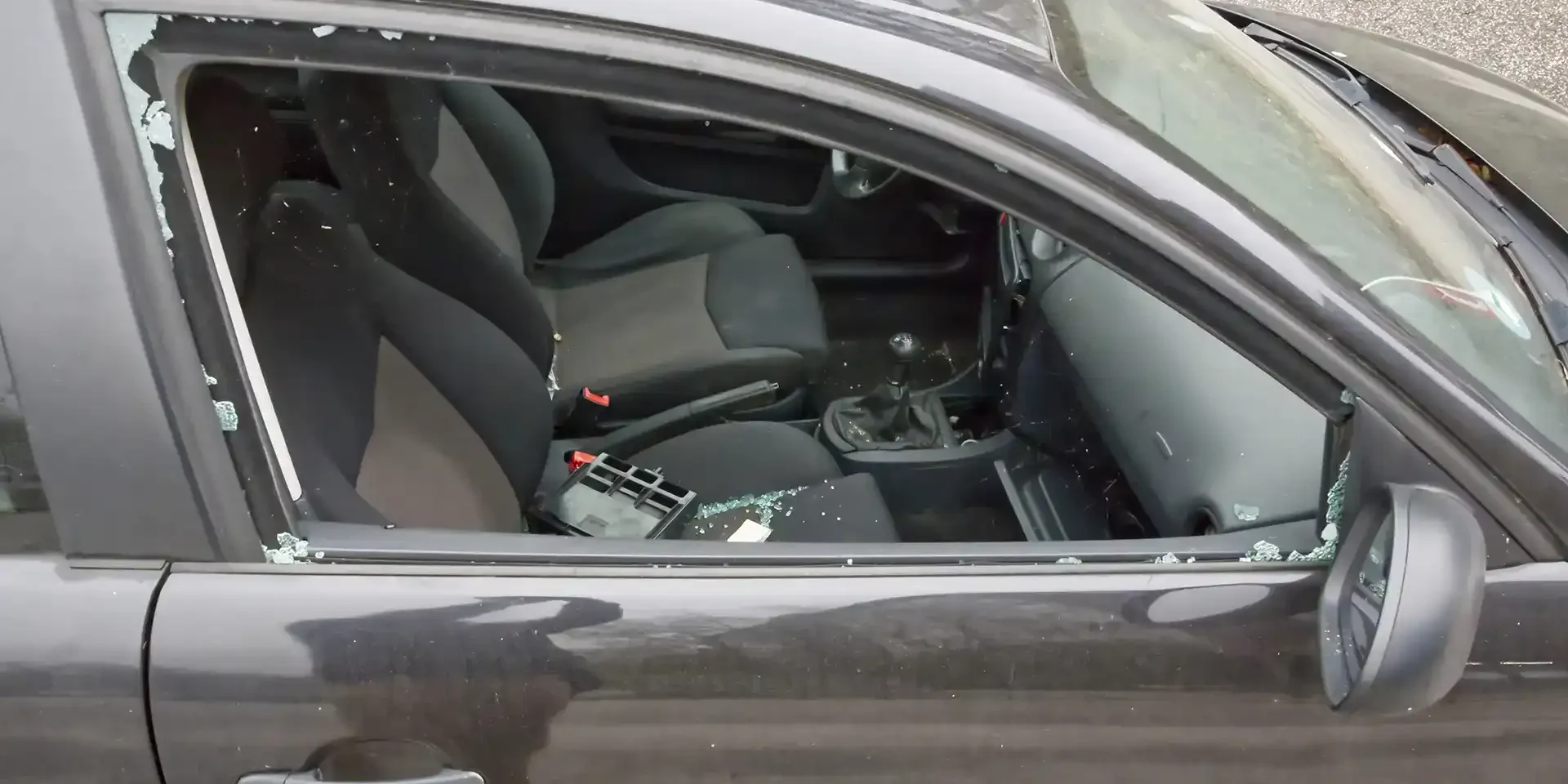 Damaged car window with shattered glass in San Antonio crime scene.
