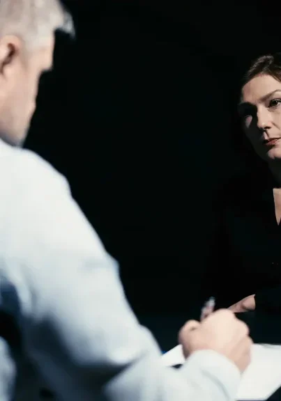 Law enforcement officer interviewing a witness in a dark setting.