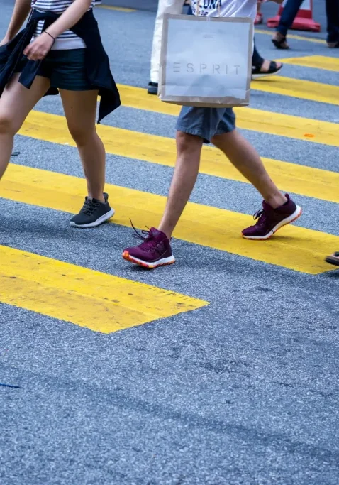 Pedestrians crossing at a busy San Antonio crosswalk with yellow stripes.