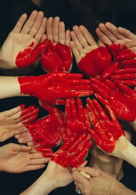Photo of many hands painted red and joined to make a red heart shape