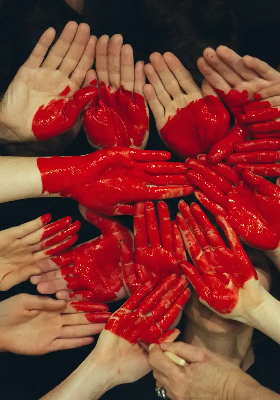 Photo of many hands painted red and joined to make a red heart shape