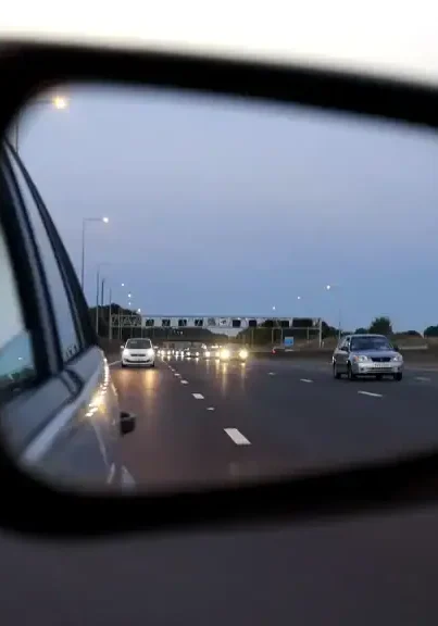San Antonio police car mirror showing highway traffic at dusk.