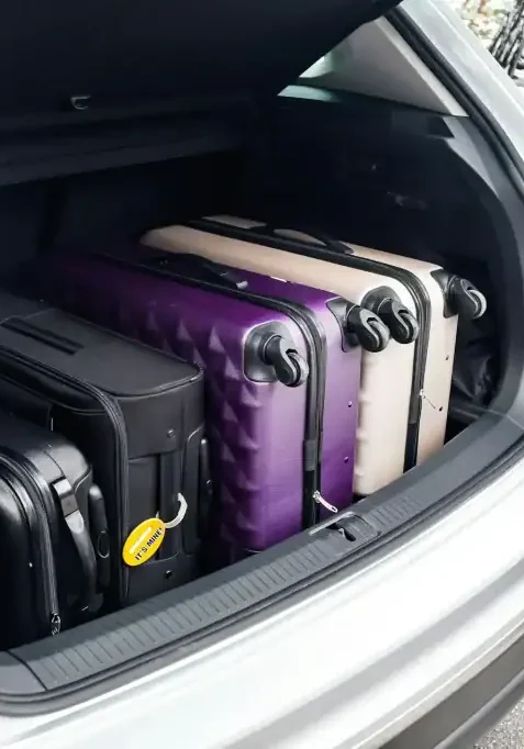 Suitcases packed in the trunk of a white vehicle, ready for travel in San Antonio.