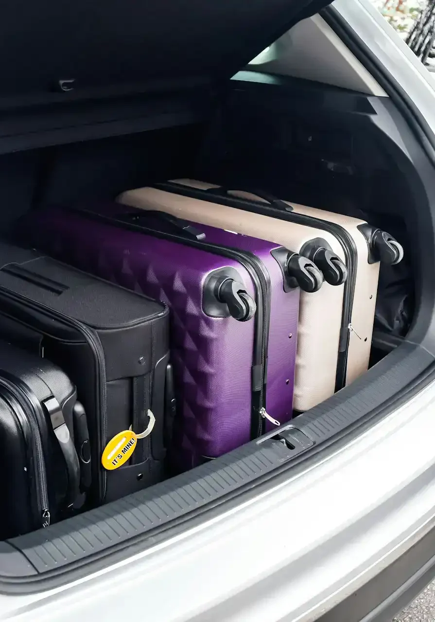 Suitcases packed in the trunk of a white vehicle, ready for travel in San Antonio.